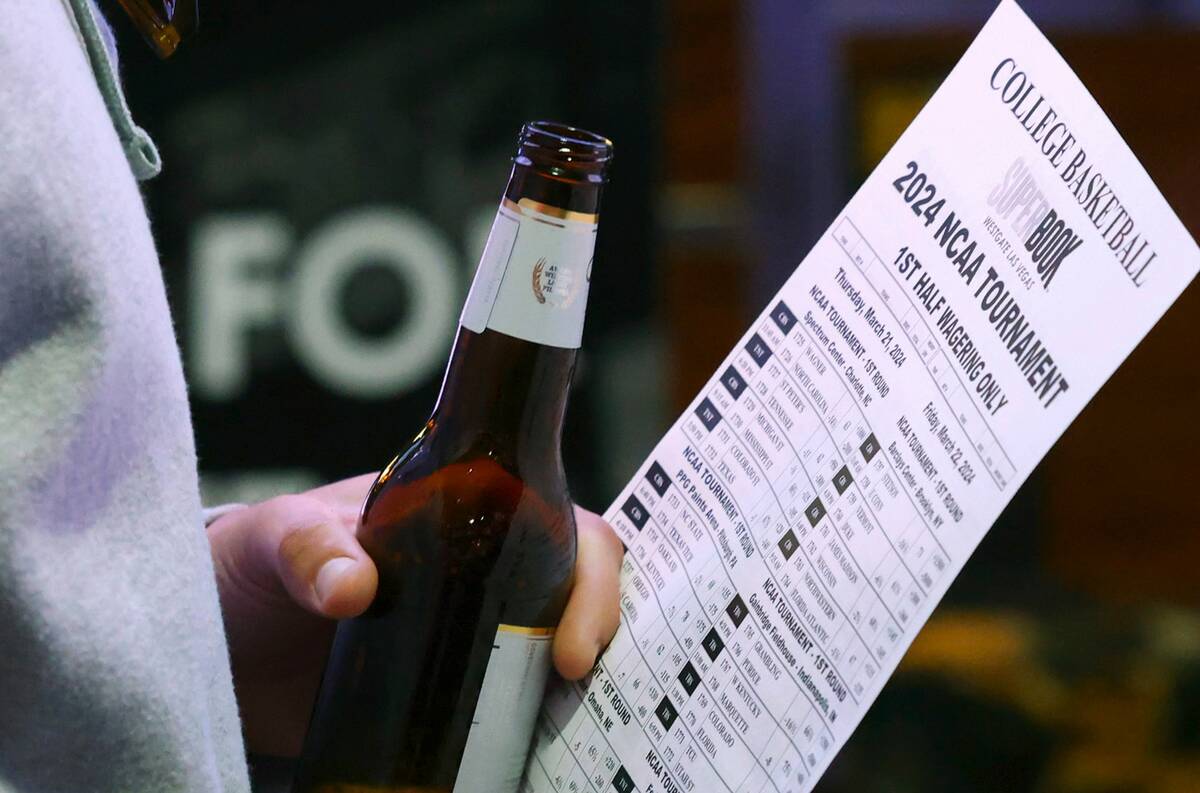 Um homem segura uma folha de apostas enquanto espera na fila para apostar no torneio de basquete da NCAA em Wes ...