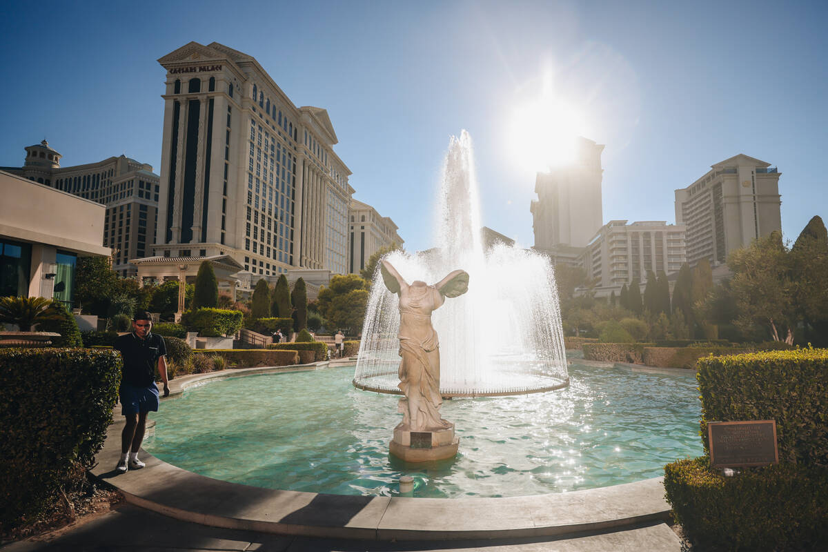 Um turista caminha perto das fontes do Caesars Palace para se refrescar enquanto o sol brilha no domingo, J ...